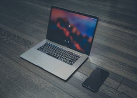 A sleek laptop and smartphone placed on wooden flooring, showcasing contemporary technology.