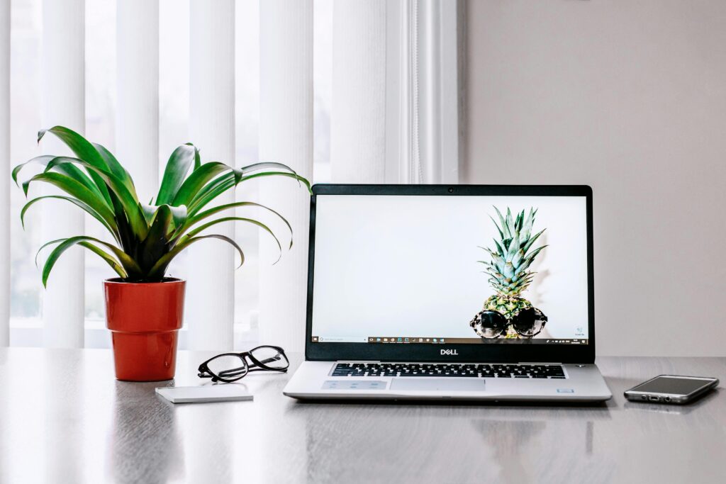 A stylish workspace featuring a laptop, plant, and smartphone on a desk.